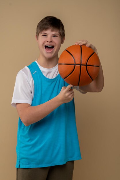 Front view of a joyful adolescent spinning the game ball on the tip of his index finger