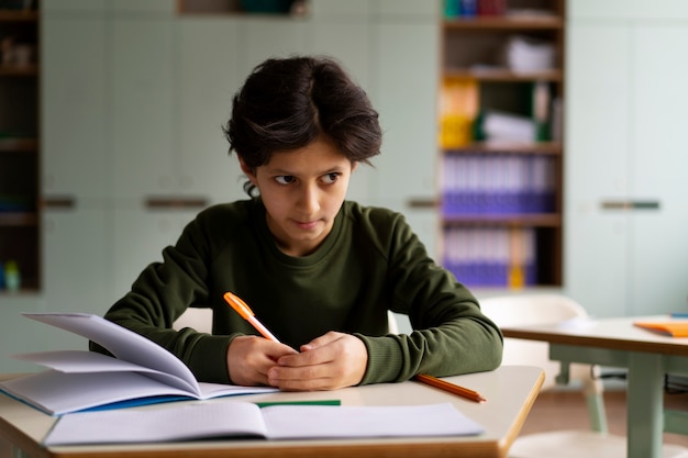 Foto bambino di vista frontale che tradisce a scuola