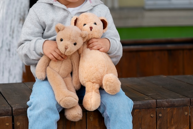 Foto vista frontale di un bambino con un orsacchiotto all'aperto