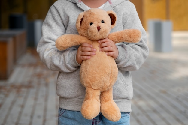 Foto vista frontale di un bambino con un orsacchiotto all'aperto