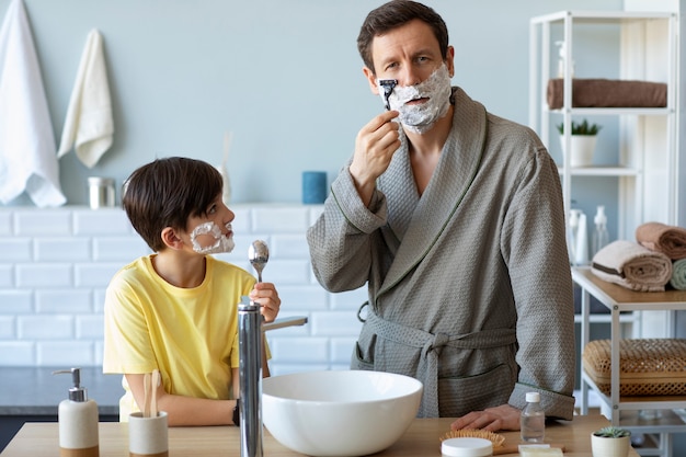 Foto ragazzo di vista frontale che guarda la rasatura del padre