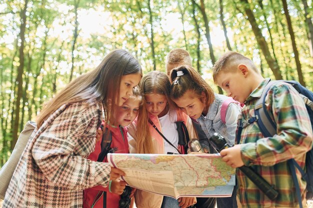 Photo front view kids in green forest at summer daytime together