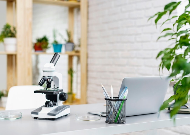 Вид спереди лабораторного стола с микроскопом и ноутбуком