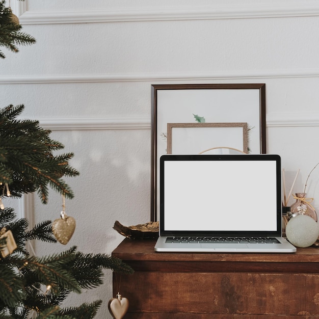 Front view of laptop computer with blank screen copy space Christmas tree with decorations Work at home