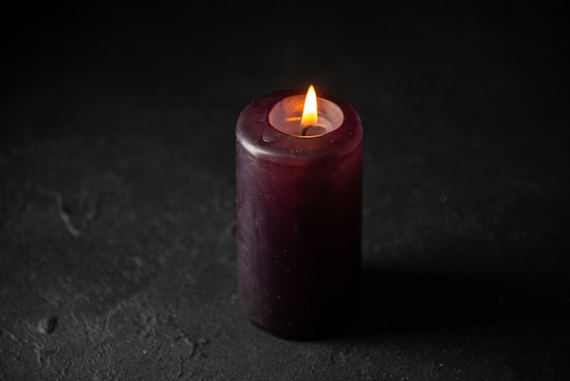 Front view of lighting candle on black