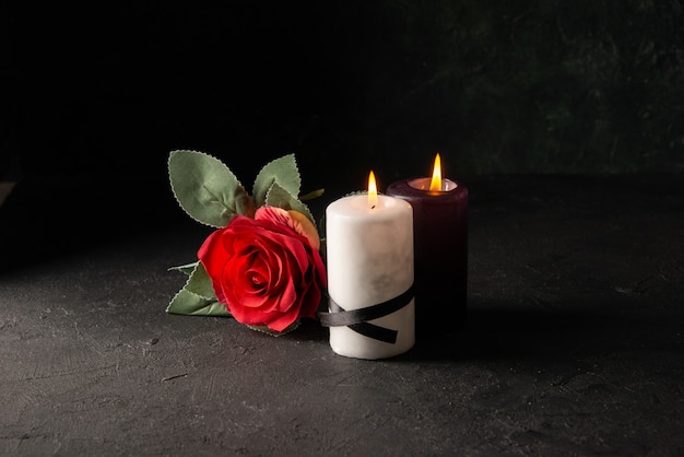 Front view of lighting candles with red flower on black