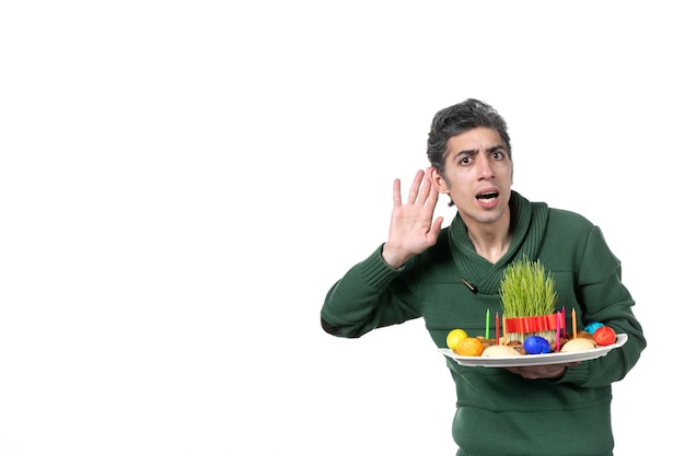 front view of listening young man holding traditional novruz xoncha on a white background colours performer ethnicity horizontal concept spring ethnic