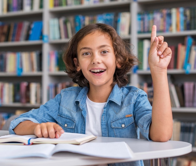 Ragazzino di vista frontale che fa i suoi compiti in biblioteca