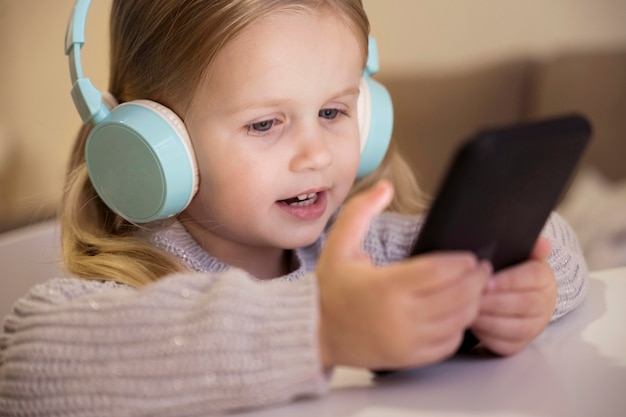 Foto vista frontale della bambina con cuffie e telefono