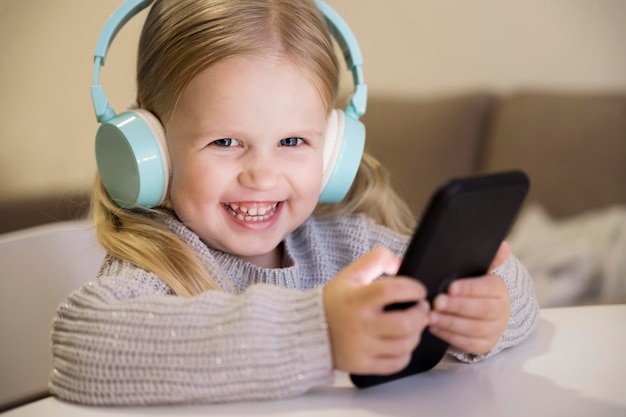 Foto vista frontale della bambina con cuffie e telefono