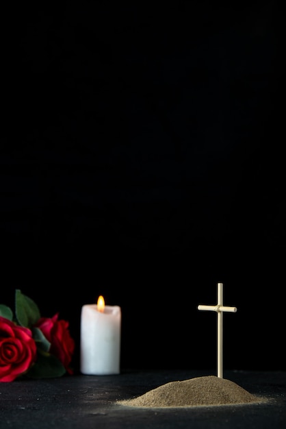 Front view of little grave with flower and candle on dark