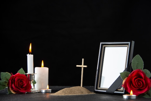 Front view of little grave with red rose and candles on black