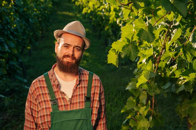 Front view looking at camera young winemaker male farmer happy wrinkles bright sun vineyard smile