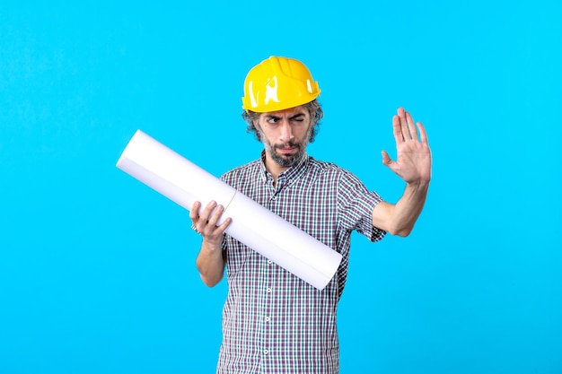 Front view male builder in helmet holding plan on blue