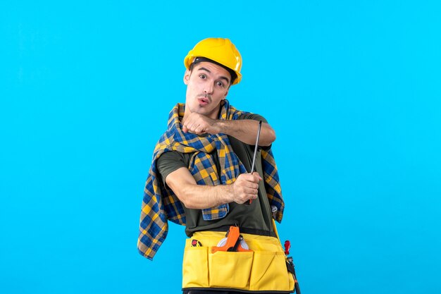 front view male builder in helmet holding screwdriver on the blue background flat architecture constructor house job building worker