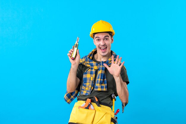 front view male builder in helmet with different tools on blue background building job architecture constructor builder house worker