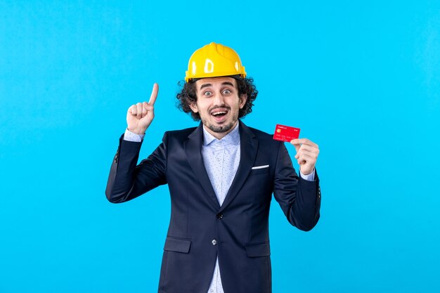 front view male builder holding bank card on blue background job business architecture constructor building engineer work