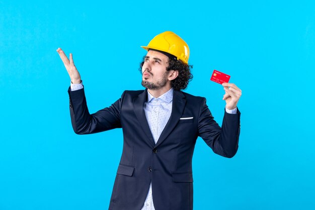 front view male builder holding bank card on blue background job business architecture constructor engineer work