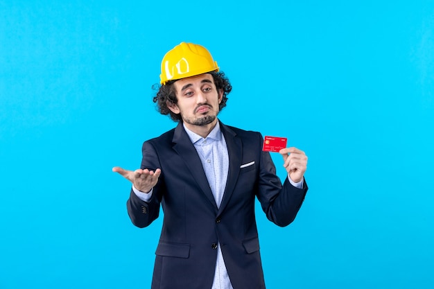 front view male builder holding bank card on blue background job business architecture work constructor building color engineer