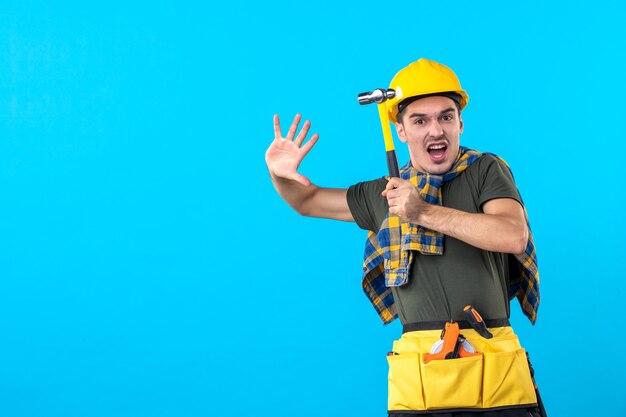 front view male builder holding hammer on a blue background house job flat building worker architecture constructor