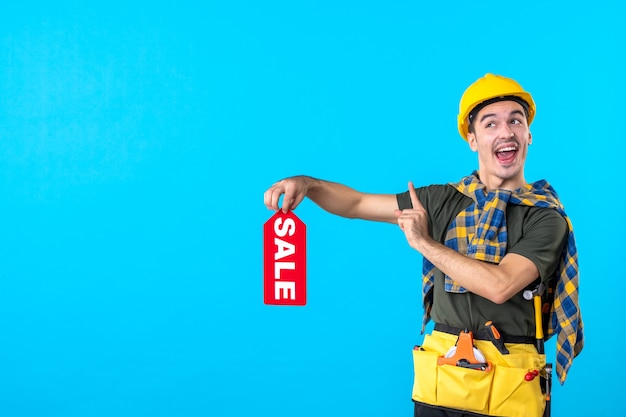 front view male builder holding red sale writing on a blue background property flat architecture constructor worker building color