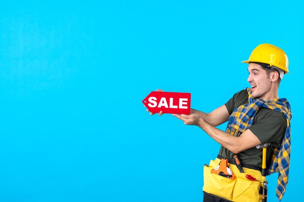 front view male builder holding sale writing on blue background flat constructor worker building property color