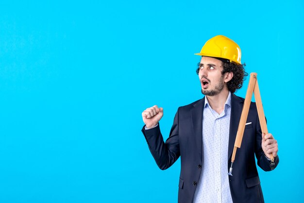 front view male builder holding wooden device on a blue background business design constructor job architecture building work