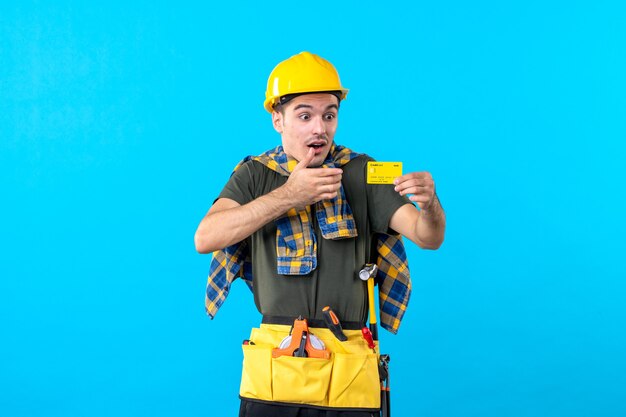 front view male builder in yellow helmet holding bank card on blue background money architecture building worker flat color