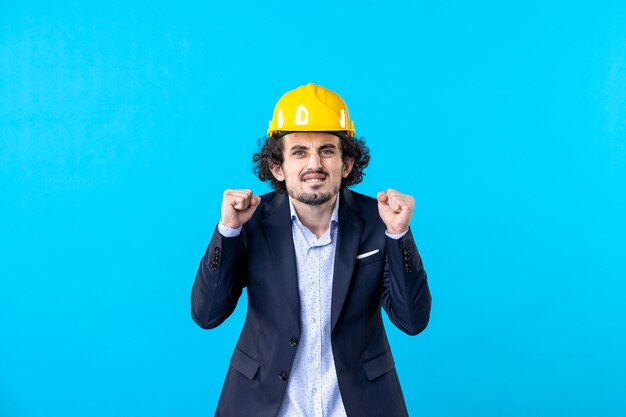 Photo front view male builder in yellow helmet and suit on the blue background architecture work job business design constructor building