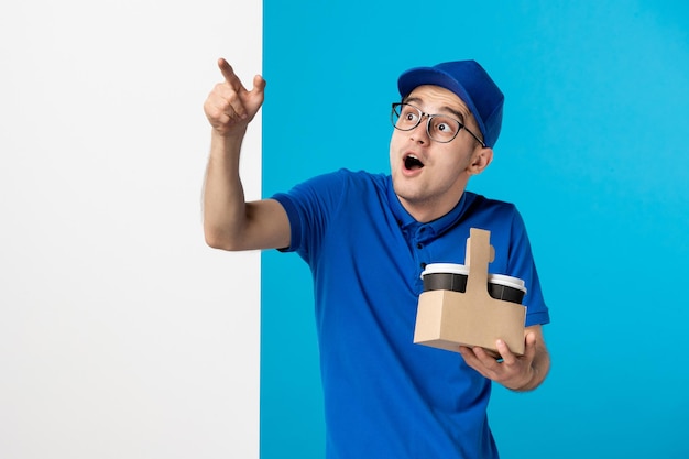 Front view of male courier with coffee on blue 