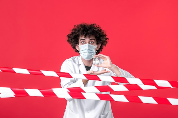 Foto vista frontale medico maschio in uniforme medica che tiene flaconi su uno sfondo rosso striscia colorata pericolo covid- avvertenza salute quarantena ospedale