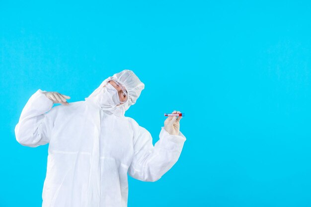 Front view male doctor in protective suit holding flask on blue