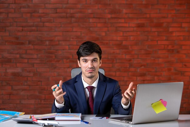 front view of male engineer sitting behind his working place with laptop in suit work plan contractor occupation builder job corporate project