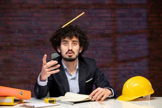 front view of male engineer sitting behind working place in suit plan business builder work occupation project corporate job