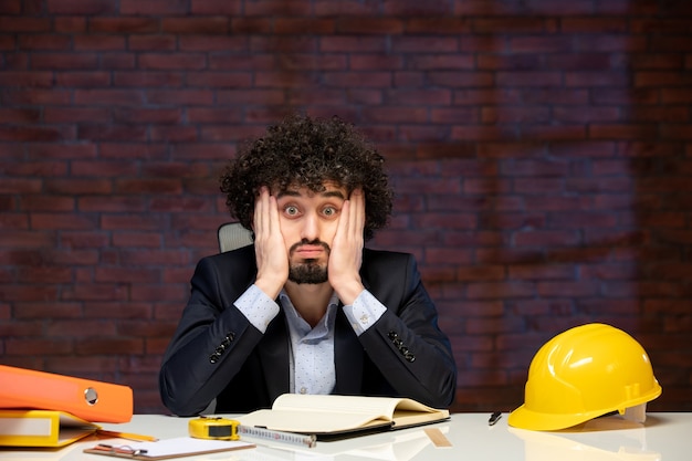 Foto vista frontale dell'ingegnere maschio seduto dietro il posto di lavoro nel piano aziendale lavoro aziendale progetto costruttore lavoro occupazione