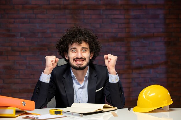 front view of male engineer sitting behind working place in suit plan business work corporate project job contractor occupation builders