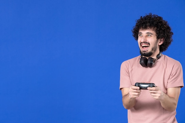 front view male gamer playing video game with gamepad on blue background winning sofa youth adult joy virtual player teen soccer