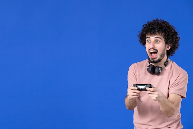 front view male gamer playing video game with gamepad on blue background winning sofa youth adult joy virtual player teen young soccer