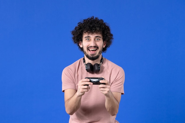 front view male gamer playing video game with gamepad on blue background young virtual teen winning player video soccer adult joy