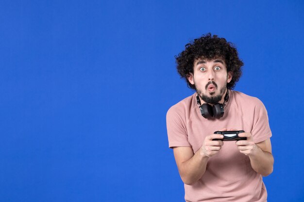 вид спереди геймер мужчина играет в видеоигру с геймпадом синий фон молодежь радость футбол диван игрок выигрывает взрослый подросток
