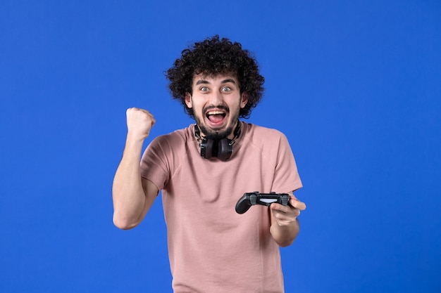 Фото Вид спереди мужчина-геймер играет в видеоигру с геймпадом на синем фоне виртуальный взрослый видео радость игрок молодой подросток выигрывает
