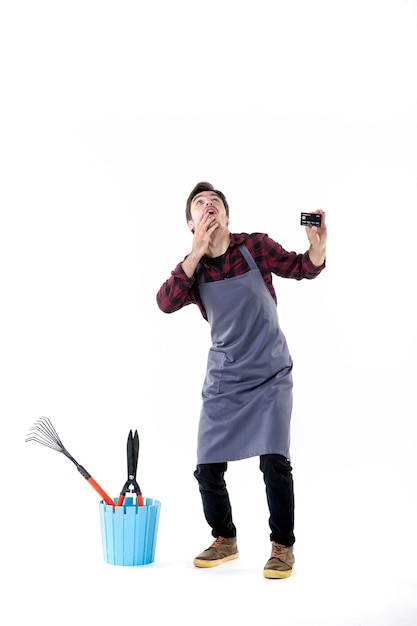 front view male gardener holding black bank card on white background work garden job uniform money soil flowers ground