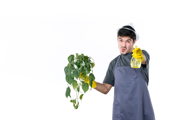 Vista frontale maschio giardiniere che tiene pianta in vaso e spray su sfondo bianco lavoro albero erba colore terra giardino fiore cespuglio