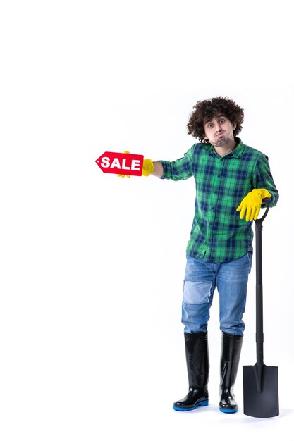 front view male gardener holding shovel and sale writing on white background grass flower field job tree garden cleaning ground dig