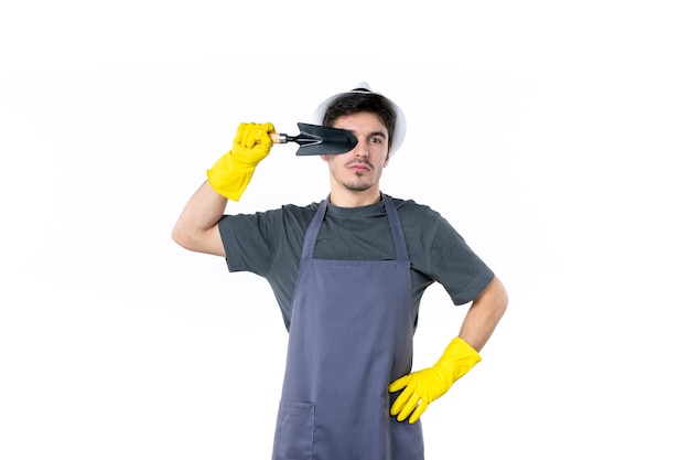 Front view male gardener in yellow gloves holding little spatula on a white background color grass flower tree job garden ground work bush