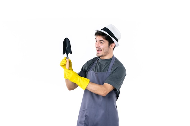 Front view male gardener in yellow gloves holding little spatula on white background work tree job garden flower bush color ground grass