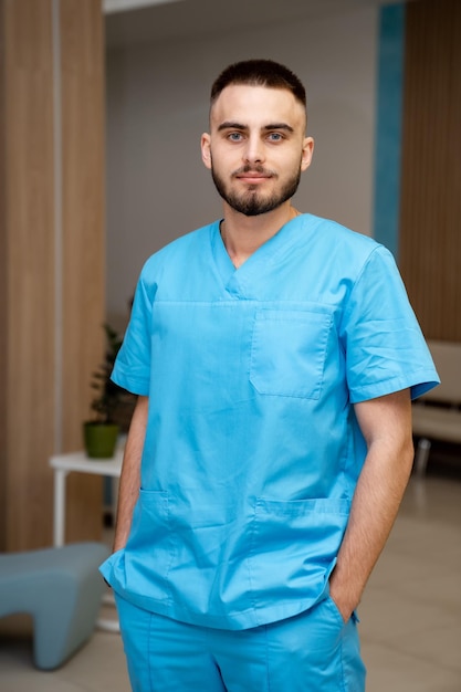 Front view of a male healthcare professional wearing scubs in a hospital. Healthcare worker in a clinic.
