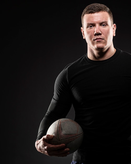 Front view of male rugby player posing while holding ball