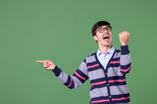 front view male teacher pointing aside with rejoicing expression on green background college woman lesson library university color school work books