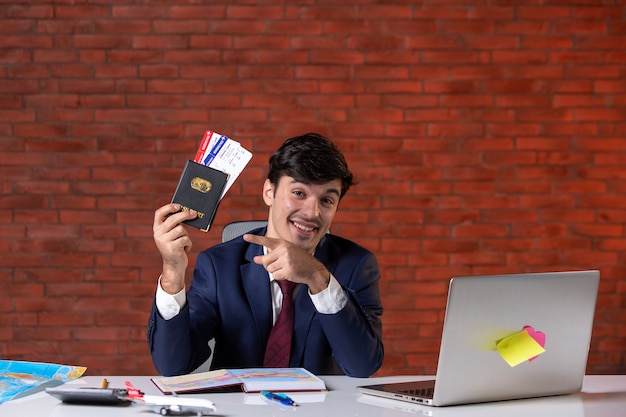 Photo front view of male worker in suit holding tickets and international passport plan contractor work business occupation tourism project job